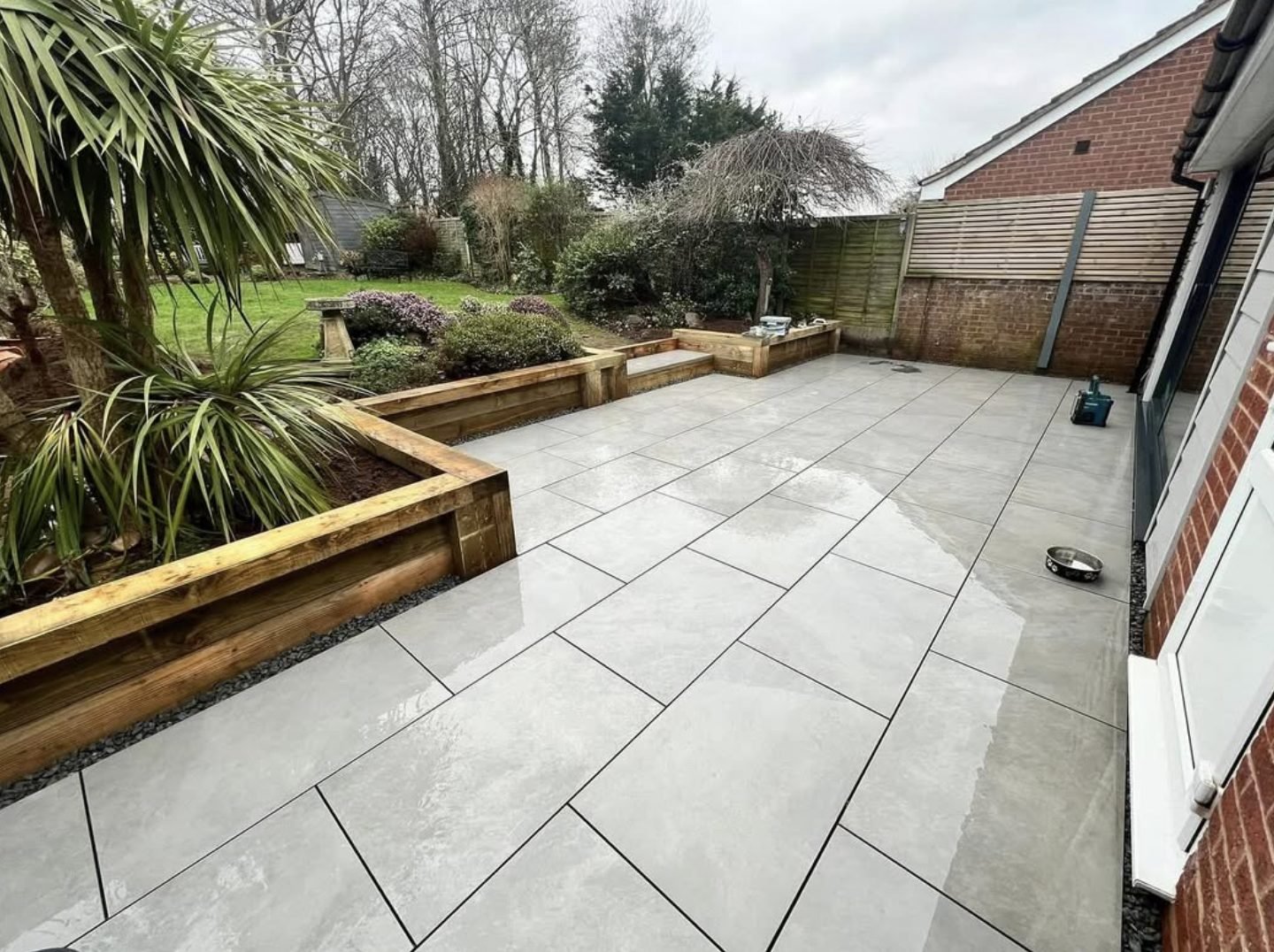Large format grey porcelain patio with timber sleeper raised beds